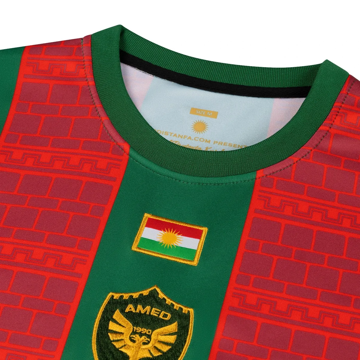 Nahaufnahme der gestickten Flagge Kurdistans und des goldenen Adler-Wappens AMED 1990 auf dem Heimtrikot